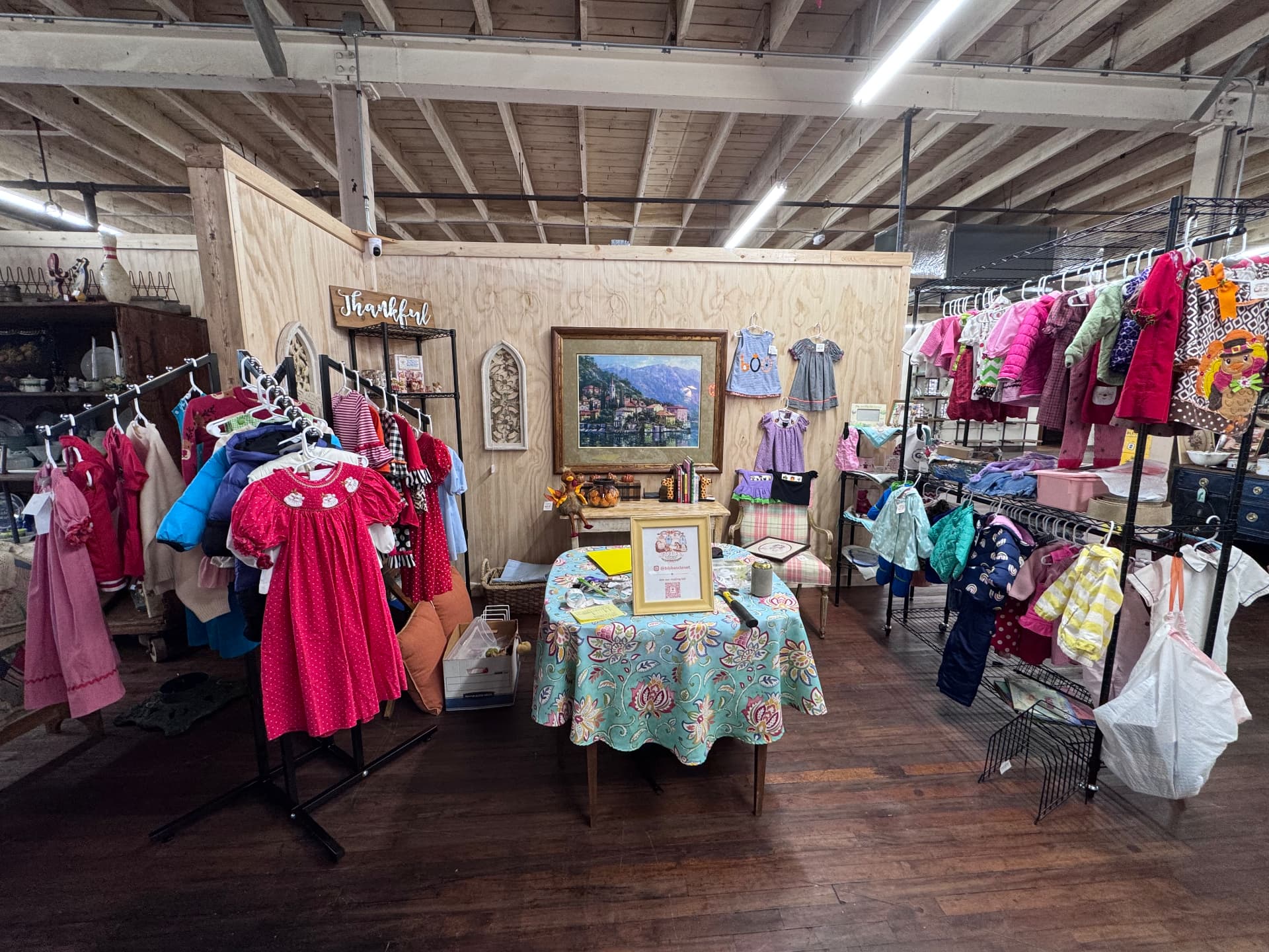 The Bibba's Closet booth at Sewell Market, with racks of children's clothing and a display table